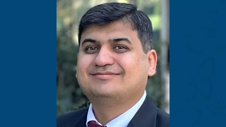 Professional headshot of Mustafa Ghazi, PhD against blue letterbox background