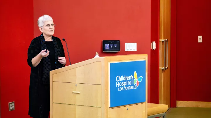 Jacqueline Szmuszkovicz, MD talk at podium in TSRI auditorium on Science Day 2024