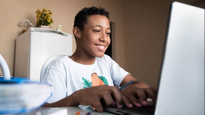 Brown_skinned_teenage_smiling_boy_at_laptop