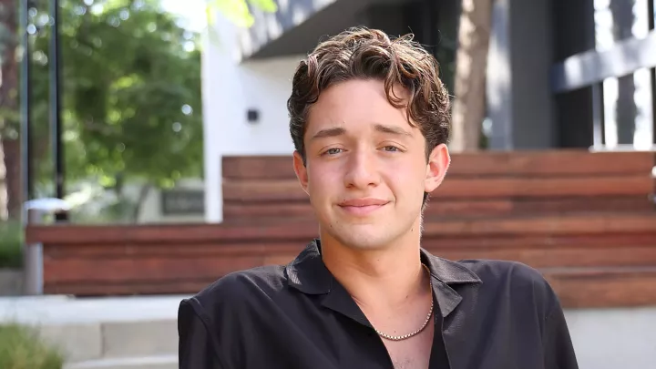 17-year-old Hunter sits in an outdoor courtyard wearing a black button down shirt. 