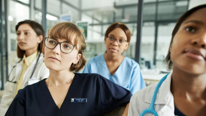 Four women in medical wear seated in classroom looking forward