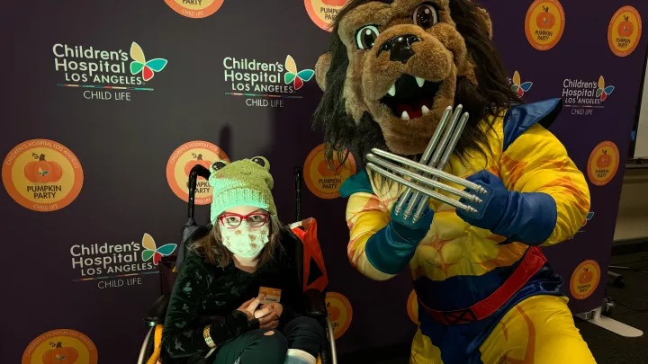 A young girl poses with the LA Kings mascot, Bailey, at the Halloween Pumpkin Party.