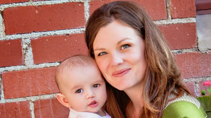 Woman with brown hair and light skin holding baby with light skin