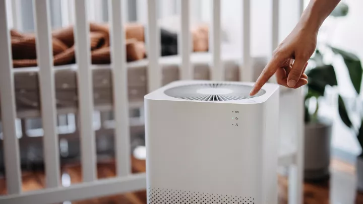 A parent turns on an air purifier in a child's bedroom. 