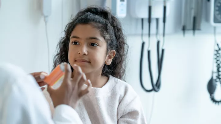 A young girl is counseled by her doctor about inhaler use for asthma.