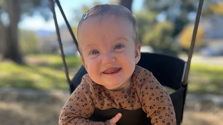 Baby wit light skin and light hair in swing with toothless smile