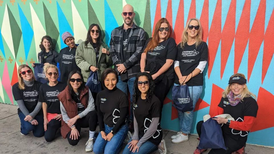 12 members of CHLA's nurse anesthetist team rest against brightly colored wall during clean-up event