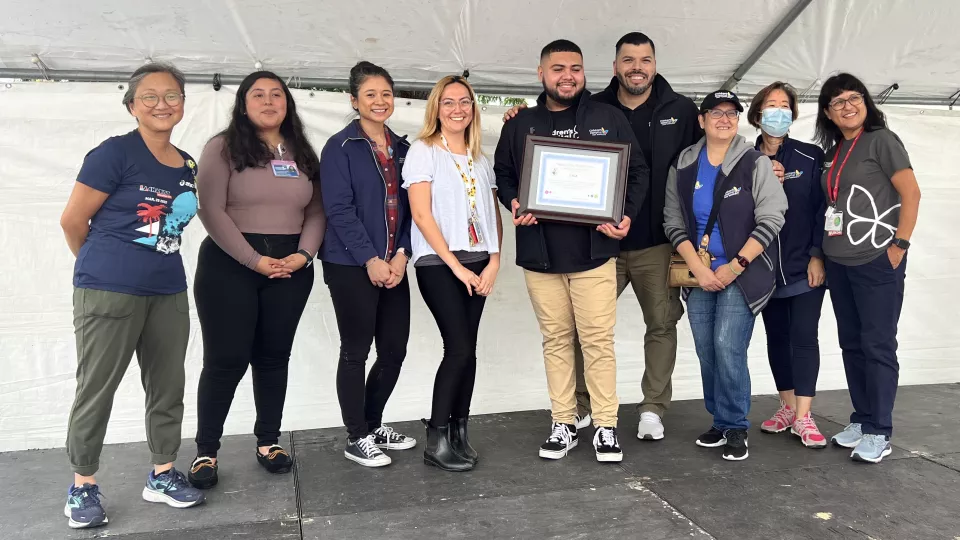 CHLA team member volunteers pose for group photo under white tarp at the 2022 Community Wellness Fair