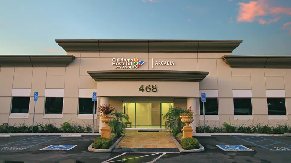 Exterior of entrance to CHLA's Arcadia Specialty Center, a one-story building with the numbers 468 on the facade beneath a blue sky with pink cloud