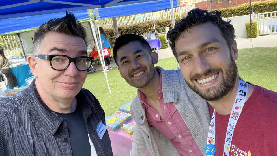 Three casually dressed men with light skin tone smile for the camera