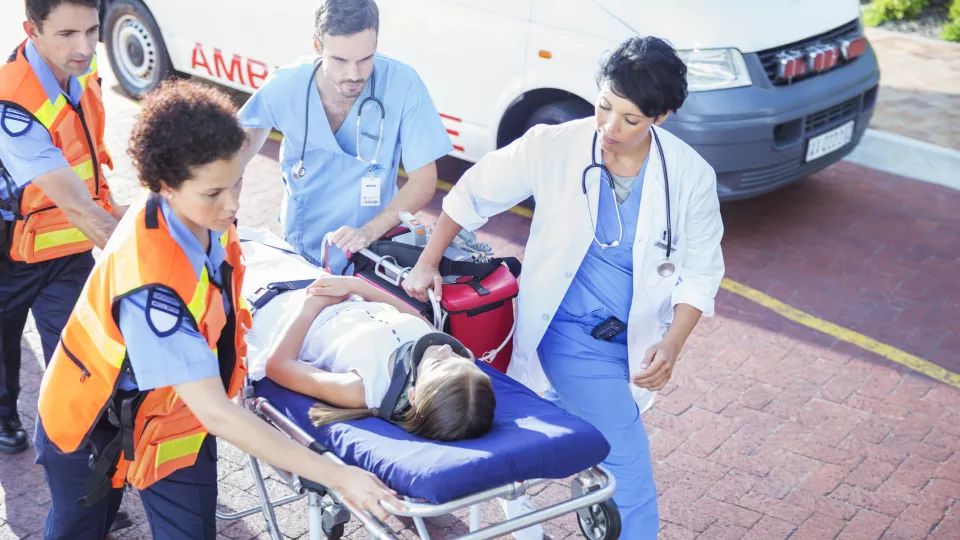 ED team pushing girl with light skin and brown hair on gurney