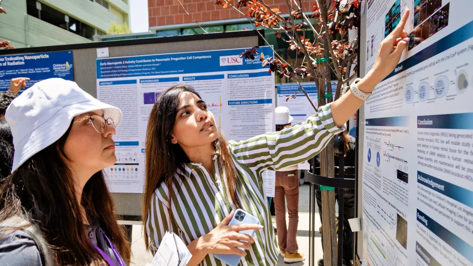 A researcher presents their poster to an onlooker at the TSRI Science Day poster session