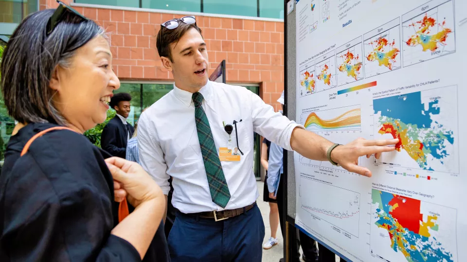 A researcher presents a poster to an onlooker at TSRI Science Day 2024.