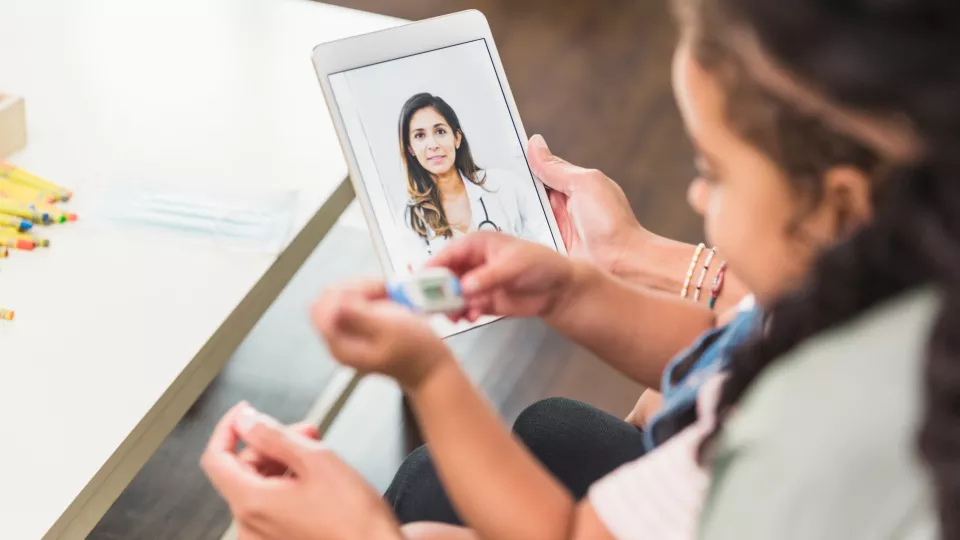 A mother and daughter have a virtual consultation with a doctor