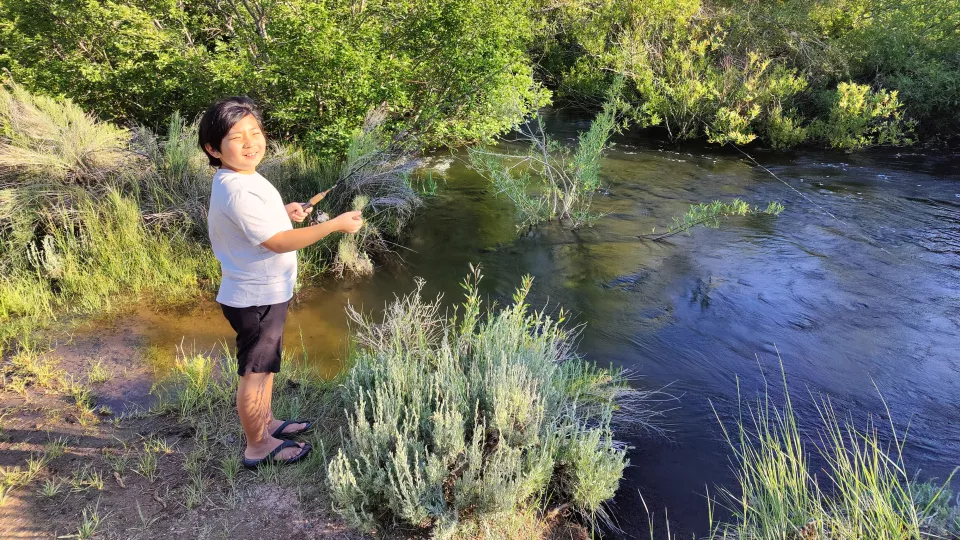 Young boy with light skin tone fishing in lake