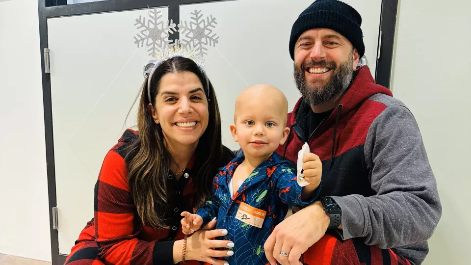 Adult woman and adult man kneeling with male toddler standing between them