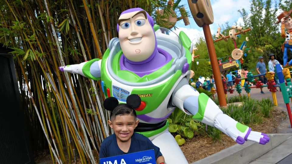 Nano, wearing mouse ears, poses with Buzz Lightyear at Disney World. 