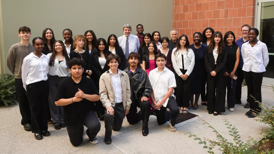 24 high schoolers pose for a photo with program administrators. 