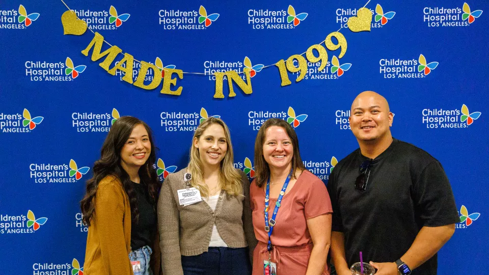 Four CHLA nurses stand smiling in front of a blue backdrop with a "Made in 1999" sign.