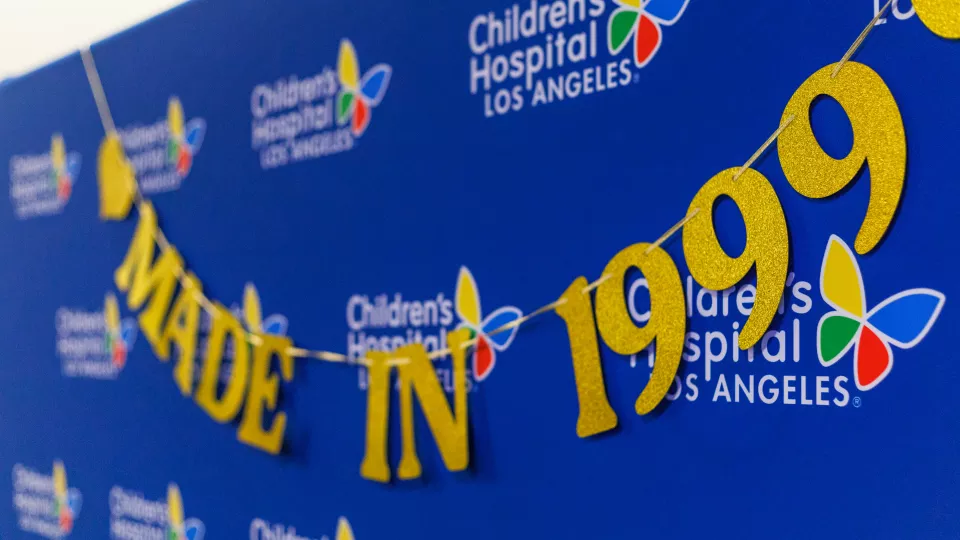 A gold letter sign reads "Made in 1999" hanging against a blue CHLA backdrop. 