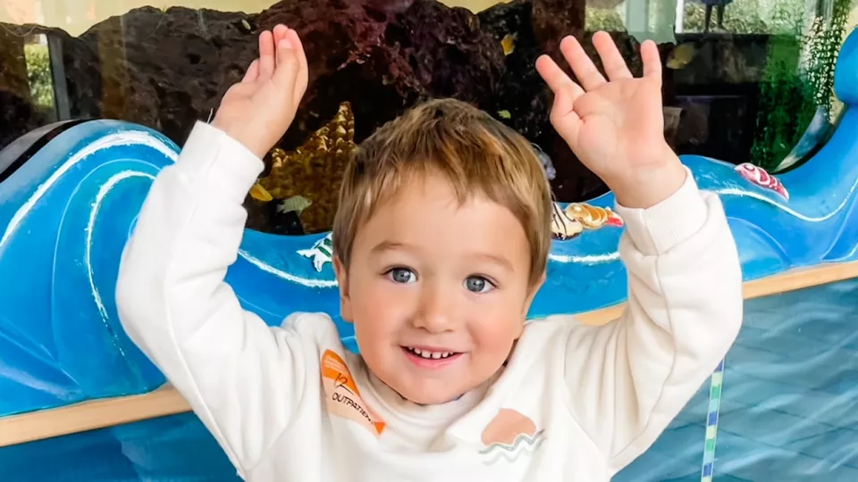 Young boy with light skin holding both arms overhead