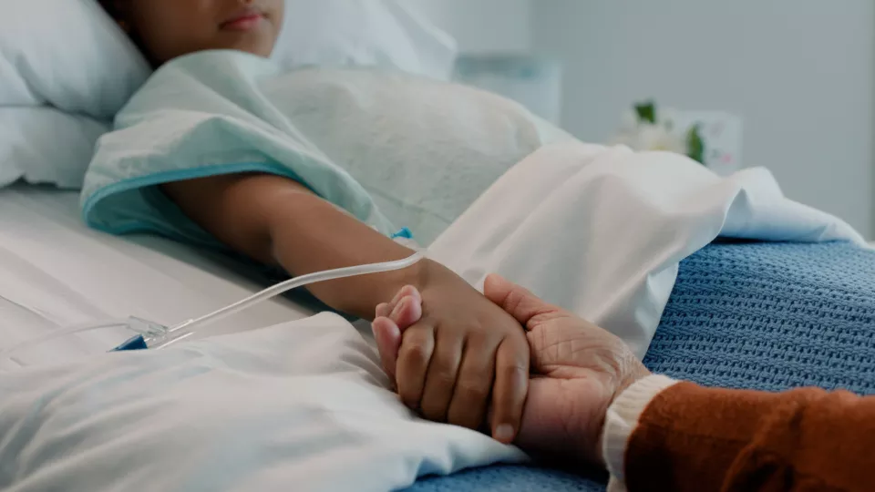 Brown-skinned_child_in hospital bed_holding_hand 