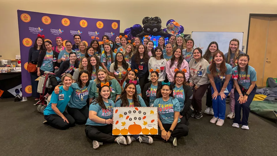 The Child Life team poses in front of the CHLA Pumpkin Party backdrop on Halloween.