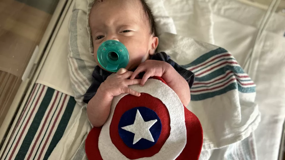 A NICCU baby wears a felt Captain America shield.