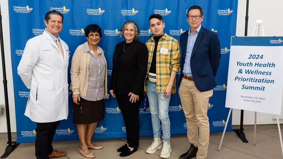 Five persons standing beside each other in front of CHLA signage