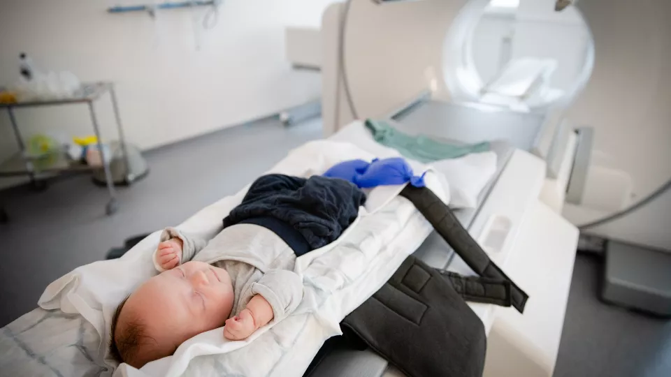 An infant lays on a medical table about to go into an MRI machine.