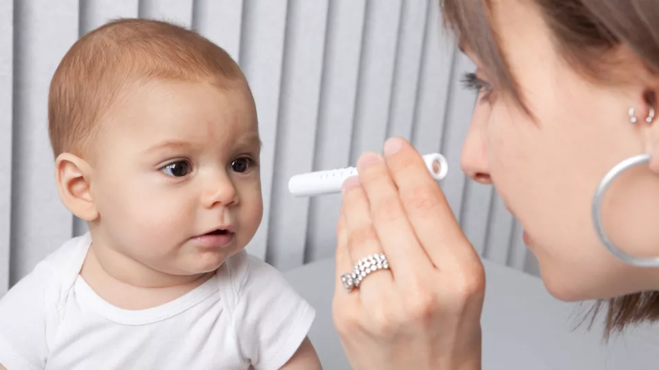 caucasian infant looking at scope held by female doctor  