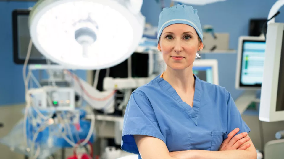 Dr. Lorraine Kelley-Quon wearing scrubs and medical cap stands in hospital operating room