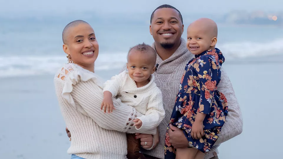 A smiling mother, father and two daughters pose for a family portrait.