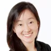 Headshot of a smiling woman with light skin tone and straight, dark hair wearing a dark top against a white background