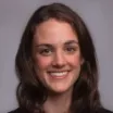 Headshot of woman with light skin tone and dark hair wearing business attire