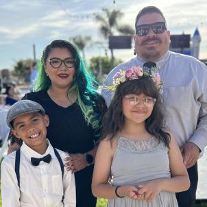 Mother and father pose with son and daughter at outdoor celebration