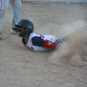 A boy in a baseball uniform, helmet and sport goggles slides in the dirt.