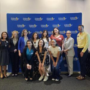 Pediatric Pathway program students pose for a picture with CHLA nursing leaders and Mount Saint Mary's Staff in front of a blue CHLA branded backdrop. 