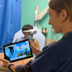 Hunt monitors the patient's view in VR using a tablet while the patient tries out the game in pre-op. 