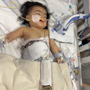 Baby lying on hospital bed sleeping, hooked up to multiple machines