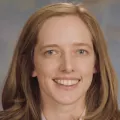 Headshot of a smiling woman with light skin tone and light brown hair wearing business attire