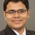 Professional headshot of Jashdeep Bhattacharjee, PhD against blue letterbox background