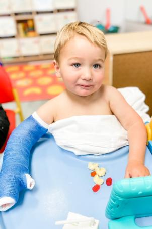 Young child with light skin and right arm covered with a blue cast