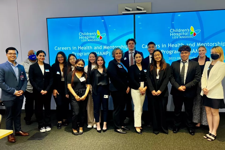 The 2023 cohort of the Careers in Health and Mentorship Program at Children’s Hospital Los Angeles pose in front of oversized digital TV monitors