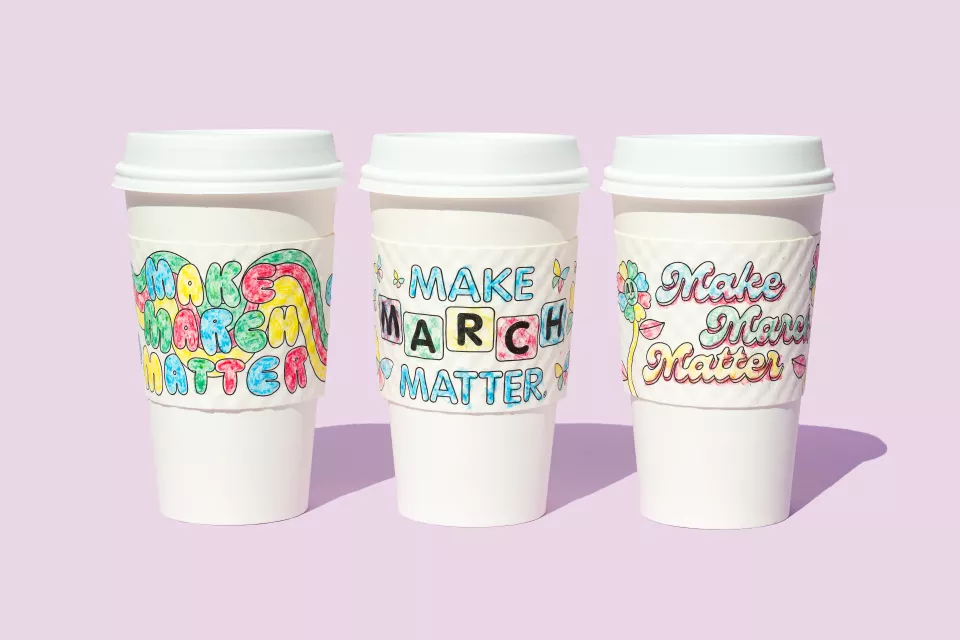 Three to-go coffee cups with brightly colored Make March Matter sleeves against a pink background