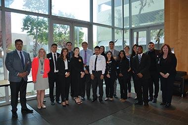 17 young adults and adults in business attire pose and smile.