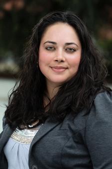 A medium skin-toned woman with dark hair smiles at the camera