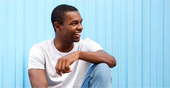 Smiling young man with dark skin tone wearing white t-shirt and blue jeans